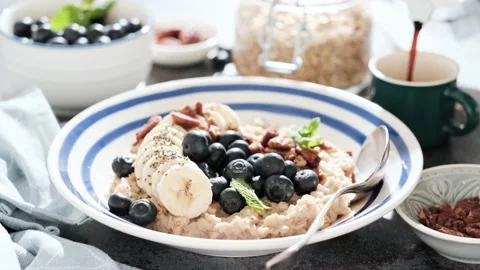 Breakfast table with oatmeal and fresh banana blueberries and pecans nuts Stock Footage 165489245