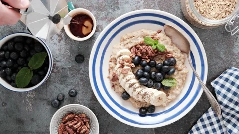Breakfast table with oatmeal and fresh banana blueberries and pecans nuts Stock Footage 165489368