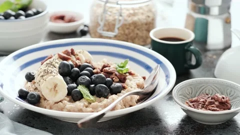 Breakfast table with oatmeal and fresh banana blueberries and pecans nuts Stock Footage 165489418