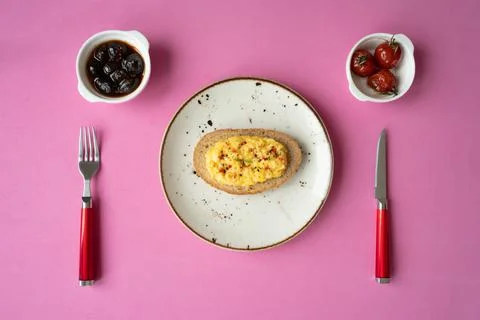 Breakfast table scrambled egg with toasted bread and black olives with sauce Stock Photos