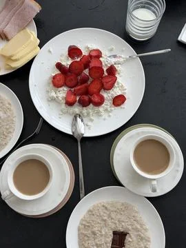 Breakfast table setting with cottage cheese topped with strawberries, oatmeal Stock Photos