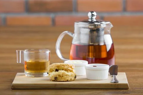 Breakfast table with tea, teapot, cup of tea, jam, bread and honey Stock Photos