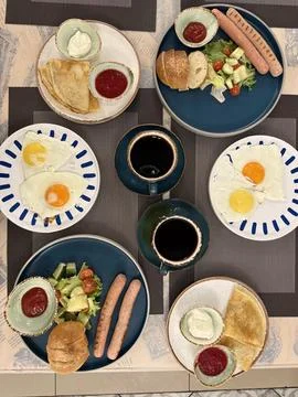 Breakfast table with various dishes including eggs, sausages, salad, bread,.. Stock Photos