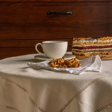 Breakfast at a table with a white tablecloth - a cup, sweet cake and walnuts Stock-Fotos