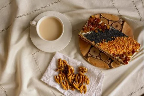 Breakfast at a table with a white tablecloth - a cup, sweet cake and walnuts Stock Photos