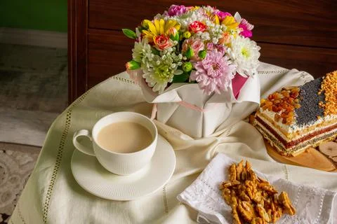 Breakfast at a table with a white tablecloth - a cup, sweet cake, walnuts and a Stock Photos