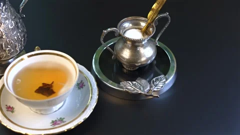 Breakfast tea served in delicate floral cup paired with vintage silverware and Stock-Footage 294930771