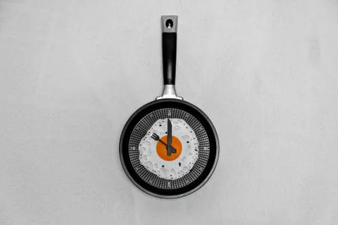 Breakfast time concept fried egg on cooking pan shaped clock on light background Stock-Fotos