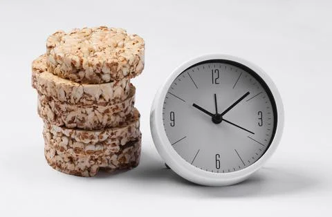 Breakfast time. Diet concept. Stack of Whole grain crispbreads and clock on w 스톡 사진