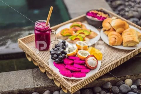 Breakfast on a tray with fruit, buns, avocado sandwiches, smoothie bowl by the Stock Photos