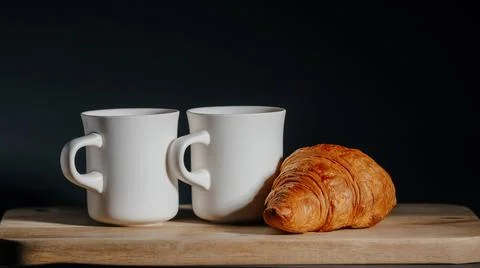 Breakfast for two. two cups of hot tea and fresh croissant Stock Photos