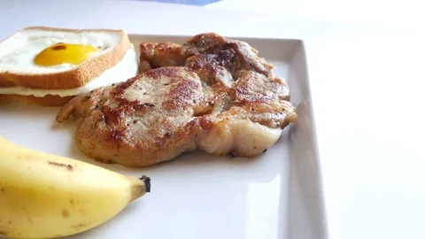 Breakfast,Include,pork steak,Fried egg, bread and banana Stock Footage 70114436