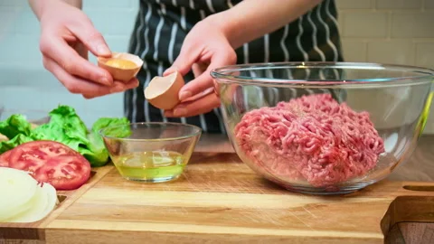 Breaking and spilling egg white and yolk and placing into beef mince in 4K. Stock Footage 153726866