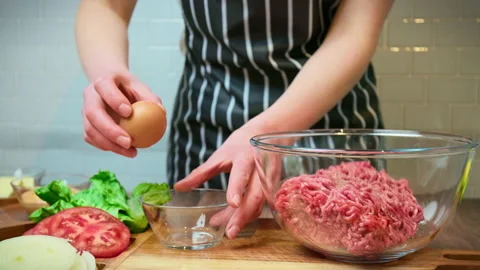 Breaking and spilling egg white and yolk and placing into beef mince in 4K. Video stock 153727148
