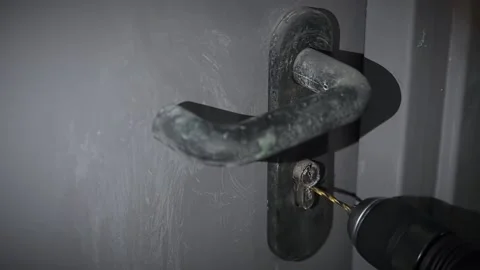 Breaking a door lock with a drill. A man drills a keyhole to open the door Stock Footage 170340436