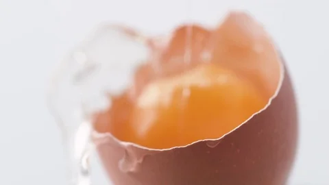 Breaking egg. Egg yolk falls into broken egg shell. Slow Motion. Stock Footage 79476356