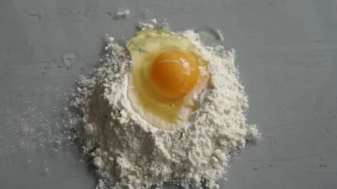 Breaking egg on flour on grey background. Stock Footage
