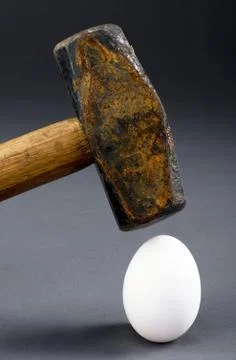 Breaking the egg with old sledge hammer. Stock Photos