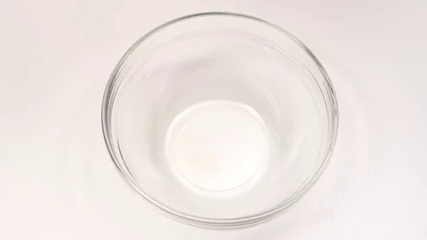 Breaking eggs for cooking in glass deep dish, white background Stock Footage 76143815