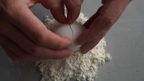 Breaking eggs on flour on grey background. Stock Footage