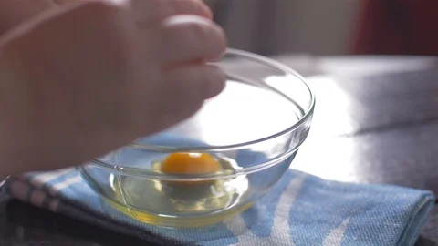 Breaking eggs into a glass bowl Видео 106473181