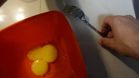 Breaking eggs in a orange plastic bowl. Fresh organic eggs falling into bowl. Pr Vidéo 113817514