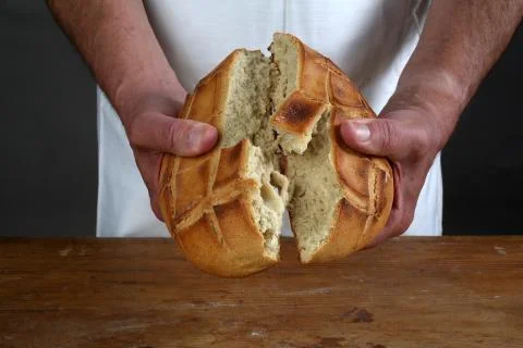 Breaking of a fresh loaf of Eucharistic bread Stock Photos