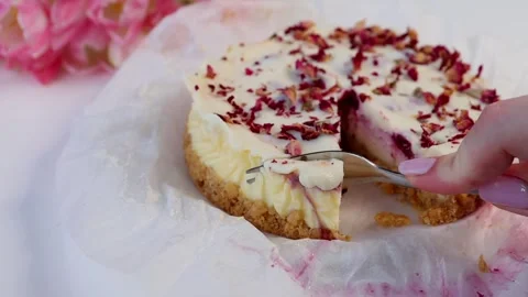 Breaking off a piece of cheesecake with a dessert fork, topped with dried rose Stock Footage 305922384