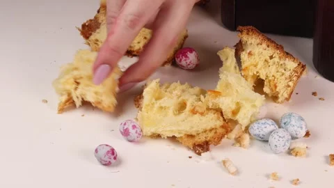 Breaking a piece of fresh Easter bread with hands next to colorful candy eggs Stock Footage 318895684