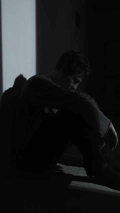 Breaking point, man sitting in darkness holding his head, overwhelmed by life Stock Footage 324817977
