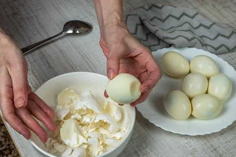Breaking the shell of a boiled white egg with an iron spoon. Removing the s.. Stock Photos