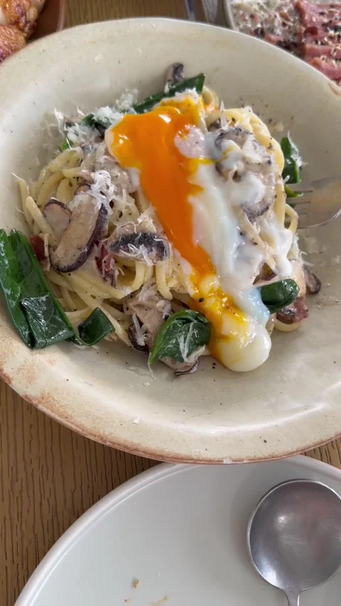 Breaking soft-boiled egg and mixing pasta with runny egg yolk Stock Footage 322970169