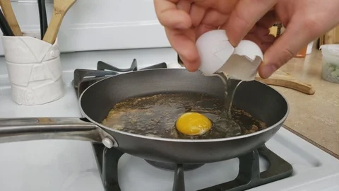 Breaking three eggs into small pan with melted and browned hot butter Stock Footage 105454512