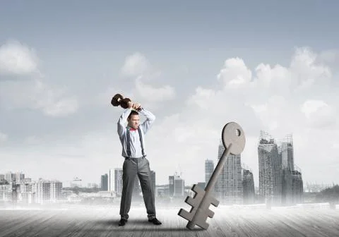 Breaking through access concept with furious man crashing concrete key 스톡 사진