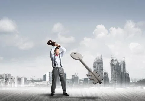 Breaking through access concept with furious man crashing concrete key 스톡 사진
