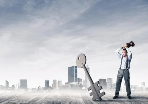 Breaking through access concept with furious man crashing concrete key 스톡 사진