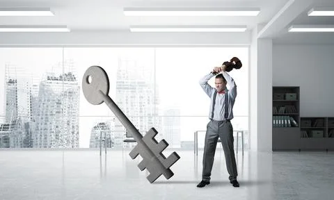 Breaking through access concept with furious man crashing concrete key 스톡 사진