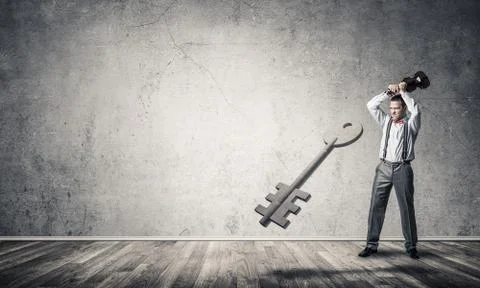 Breaking through access concept with man in room crashing concrete key 스톡 사진