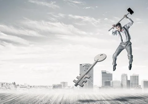 Breaking through access concept with man in anger crashing concrete key Stock Photos