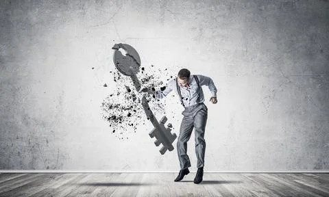 Breaking through access concept with man in room crashing concrete key 스톡 사진
