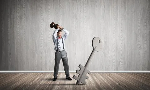 Breaking through access concept with man in room crashing concrete key 스톡 사진