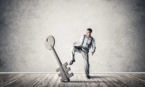 Breaking through access concept with man in room crashing concrete key 写真素材