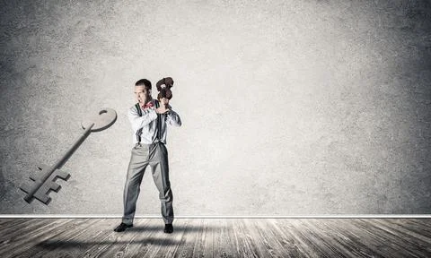 Breaking through access concept with man in room crashing concrete key Stock Photos