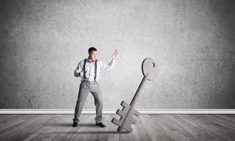 Breaking through access concept with man in room crashing concrete key Det... Stock Photos