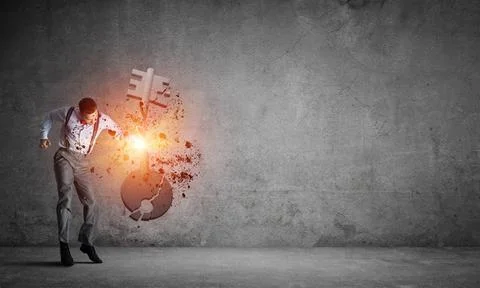 Breaking through access concept with man in room crashing concrete key Det... Stock Photos