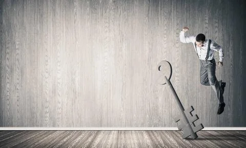 Breaking through access concept with man in room crashing concrete key Det... Stock Photos