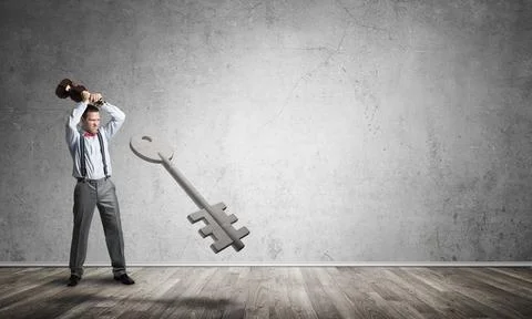 Breaking through access concept with man in room crashing concrete key 스톡 사진