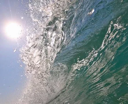 Breaking wave against the sun Stock Photos