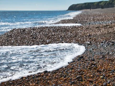 Breaking wave on the pebbled 'Blast Beach' at Seaham, lone man in the dstance. Stock Photos