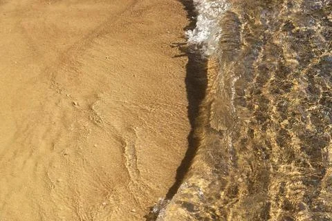Breaking wave on the sandy seashore, View from the top. Background. Stock Photos
